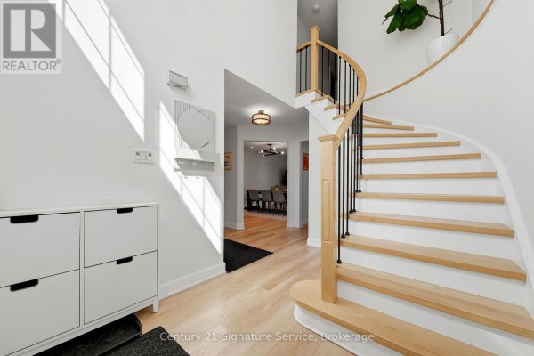 Foyer with white shoe cabinet, mirror, and curved staircase with light wood treads and black spindles. - 8 - 500 Silverthorne Crescent, Mississauga