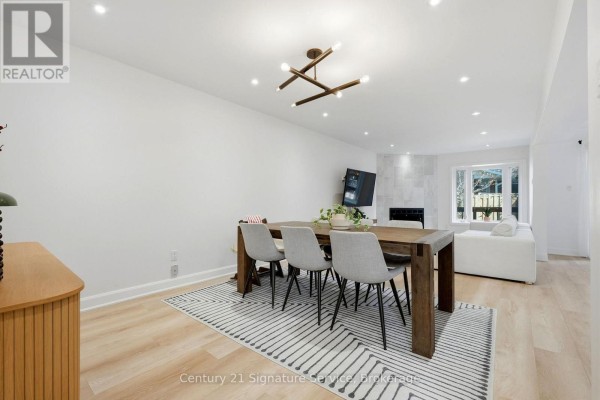 Dining area with a wooden table, grey chairs, patterned rug, and a fireplace in the background. - 8 - 500 Silverthorne Crescent, Mississauga
