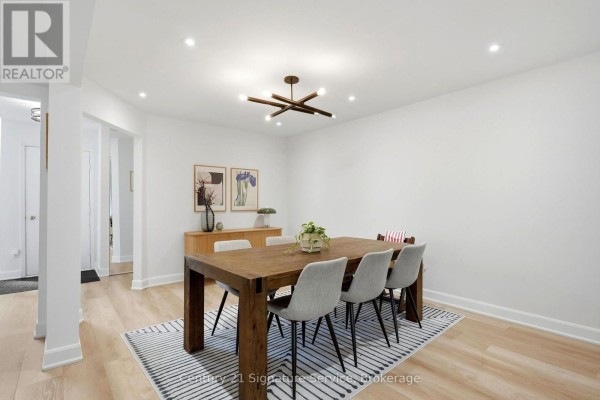 Dining room with a wooden table and chairs, a buffet, and artwork on the white walls. - 8 - 500 Silverthorne Crescent, Mississauga