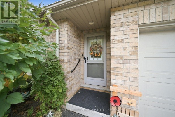 Close-up of the front entrance with a beige brick facade and a screen door. - 8 - 633 Park Road N, Brantford