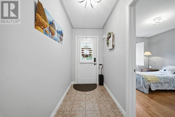 Foyer with light grey walls, tiled floor, and a view into a bedroom. - 8 - 633 Park Road N, Brantford