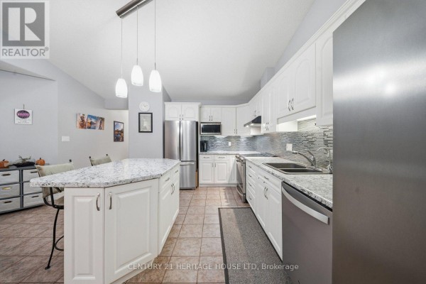 White kitchen with granite countertops, stainless steel appliances, and a large island. - 8 - 633 Park Road N, Brantford