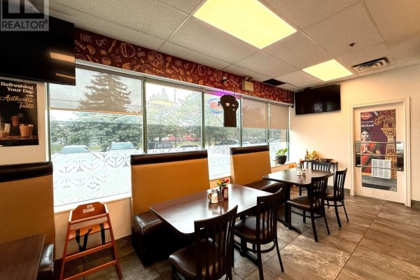 Restaurant seating area with booth and table seating, large windows with patterned blinds, and televisions on the wall. - 8 - 6740 Davand Drive, Mississauga