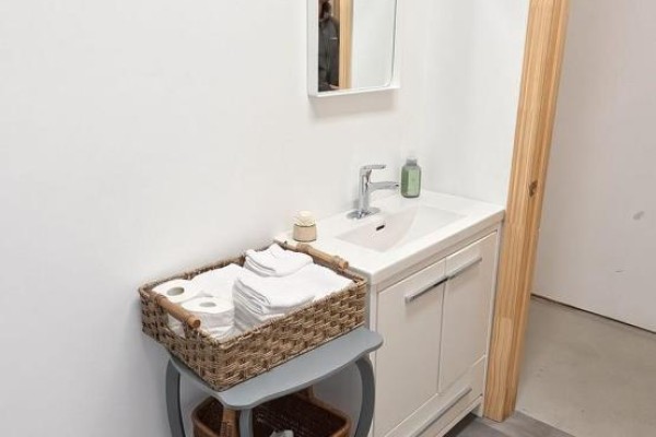 Close-up of a bathroom vanity with a white sink, white cabinetry, and a basket of towels. - 8 - 8021 35 Highway, Kawartha Lakes