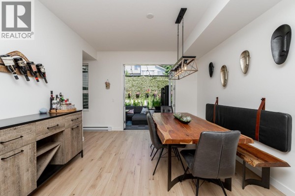 Dining room with a live-edge wood table, grey chairs, a buffet, and a view of the backyard patio. - 8 1228 Hudson Street, Coquitlam