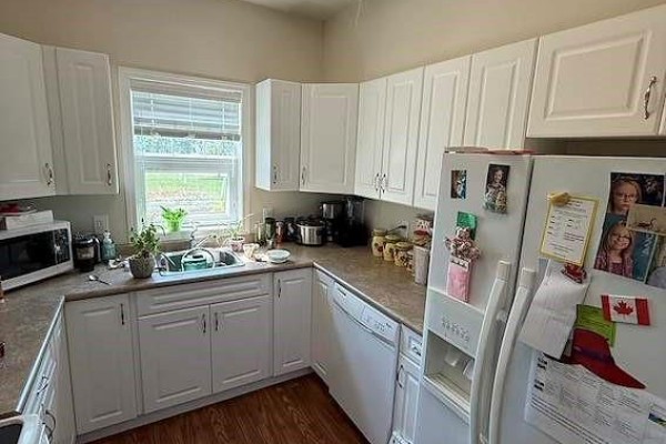 Kitchen with white cabinets, countertops, sink, microwave, dishwasher, and refrigerator. - 8 1802 106th Street, North Battleford