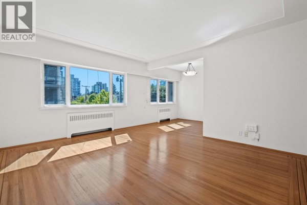 Apartment interior showing a small kitchen with light wood cabinets and an adjacent living area. - 8 2296 W 39th Avenue, Vancouver