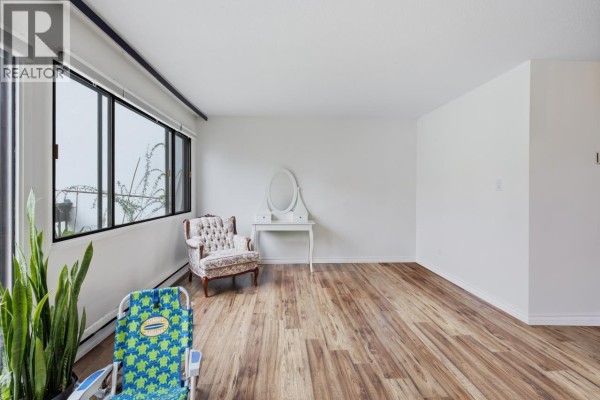 Living room with a large window, an armchair, a vanity table, and storage. - 8 7363 Montecito Drive, Burnaby