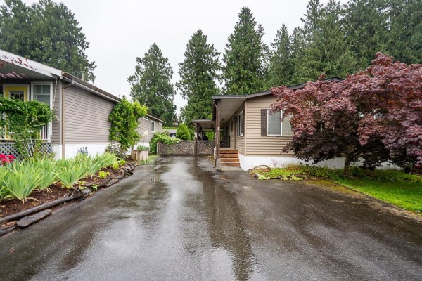 Driveway leading to a mobile home surrounded by trees and garden beds. - 8 52324 Yale Road, Popkum, Rosedale