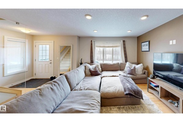 Carpeted staircase leading to a landing with three framed color artworks on the wall. - #8 9535 217 St Nw, Edmonton