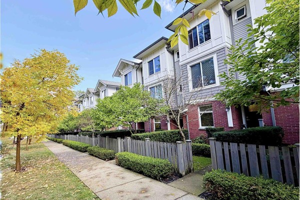 View of townhouse complex exterior with gray siding, red brick, and wooden fences. - 8 9718 161a Street, Surrey