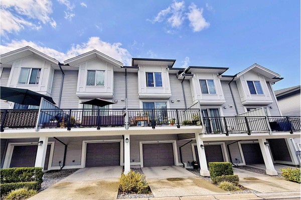 Rear exterior of townhouses showing balconies, garages, and concrete driveway. - 8 9718 161a Street, Surrey