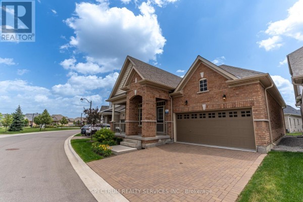 Exterior view of a brick house with a covered porch, beige siding, and a double garage door. - 8 Abelia Street, Brampton