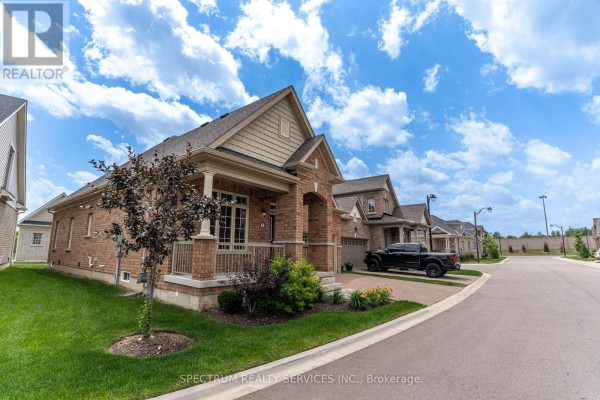 Side exterior view of a brick house with a covered porch, beige siding, and a double garage. - 8 Abelia Street, Brampton