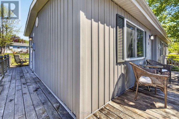 Side view of the home's beige siding, windows, and wooden deck. - 8 Belle Isle Arm, Innisfil