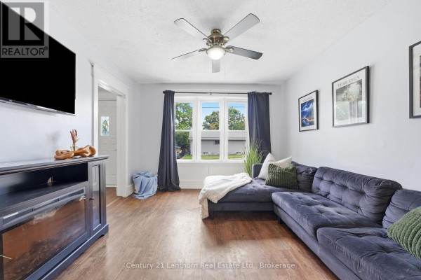 Living room with a dark blue sectional sofa, a ceiling fan, and a large window. - 8 Bettes Street, Belleville