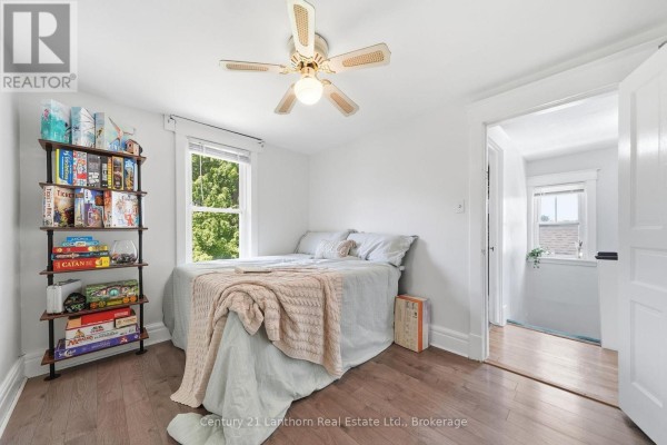 Bedroom with a queen-size bed, a bookshelf filled with board games, and a ceiling fan. - 8 Bettes Street, Belleville