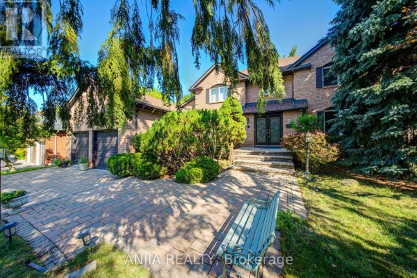 Tan brick house with a paved driveway, green shrubs, and a weeping tree. - 8 Calderbridge Crescent, Markham