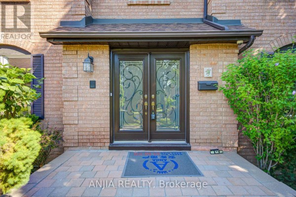 Close-up of the tan brick house entrance with double glass doors and a welcome mat. - 8 Calderbridge Crescent, Markham