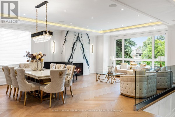 A large dining and living room with a marble fireplace and herringbone wood floors. - 8 Canary Crescent, Toronto
