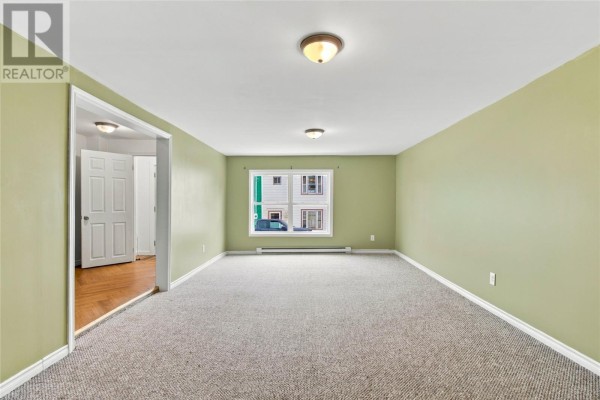 Living room with light green walls, beige carpet, a large window, and doorways to the hallway and another room. - 8 Charlton Street, St  John S
