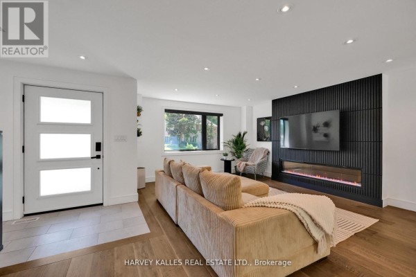 Living room with beige sectional sofa, modern fireplace, and large black entertainment unit. - 8 Circle Ridge, Toronto