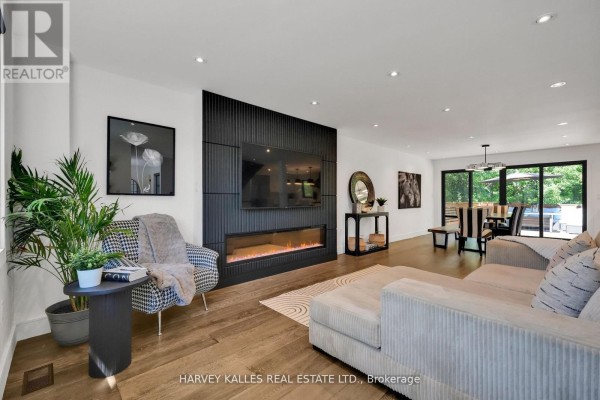 Living and dining area with fireplace, sectional sofa, dining table, and patio doors. - 8 Circle Ridge, Toronto