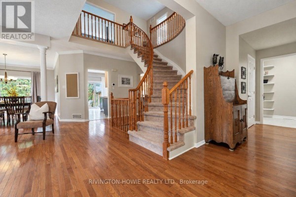 Spacious foyer with hardwood floors, carpeted staircase, and a wooden cabinet. - 8 Colindale Avenue, Ottawa