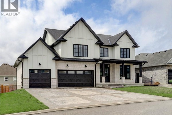 Exterior view of a modern white farmhouse style house with black trim and garage doors. - 8 Edgeview Crescent, Komoka