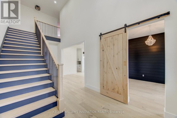 Interior view of a foyer and staircase with a blue-accented staircase and barn door entrance. - 8 Edgeview Crescent W, Middlesex Centre