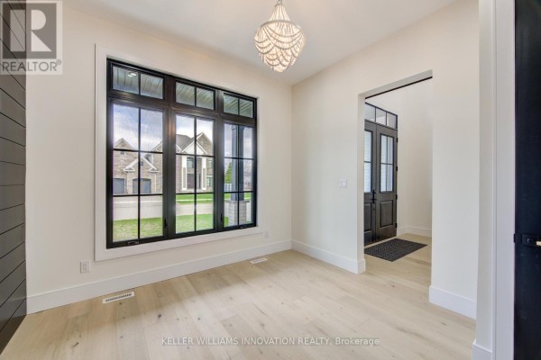 Bright room with a large window overlooking the street, wood floors, and a decorative chandelier. - 8 Edgeview Crescent W, Middlesex Centre