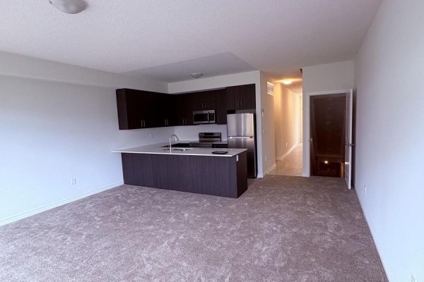 Modern kitchen with dark wood cabinets and stainless steel appliances. - 8 Elite Crescent, Haldimand