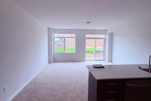 Living area with neutral carpet, large windows, and sliding glass doors. - 8 Elite Crescent, Haldimand