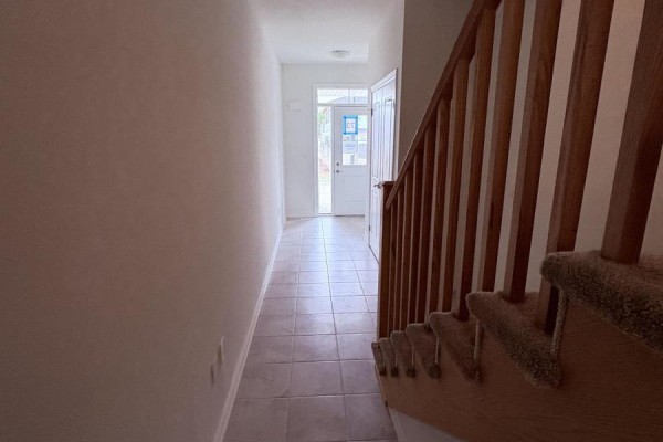 Interior hallway with tiled floor, white walls, and wooden staircase. - 8 Elite Crescent, Haldimand