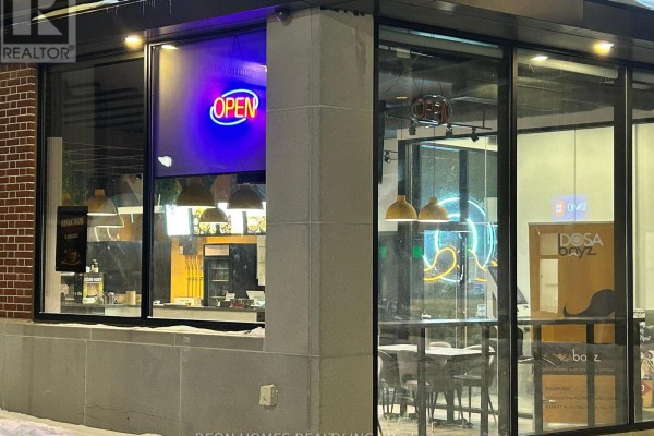 View of a restaurant interior showing rows of tables, yellow booth seating, and pendant lights. - 8 Erb Street W, Waterloo
