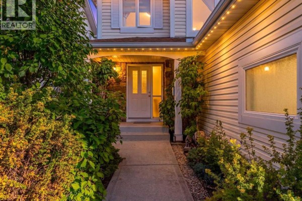 Close-up of the front entrance of a house, featuring a covered porch and stone accents. - 8 Hawkdale Close Nw, Calgary