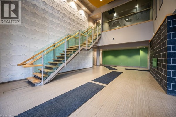 Interior view of a building lobby with a modern wood and glass staircase. - 8 Hickory Street W Unit# 404, Waterloo