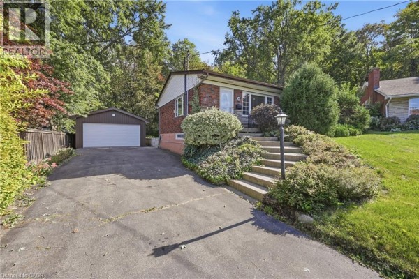 View of the house's front entrance with stone steps, landscaping, and a detached garage. - 8 Hill Place, Stoney Creek