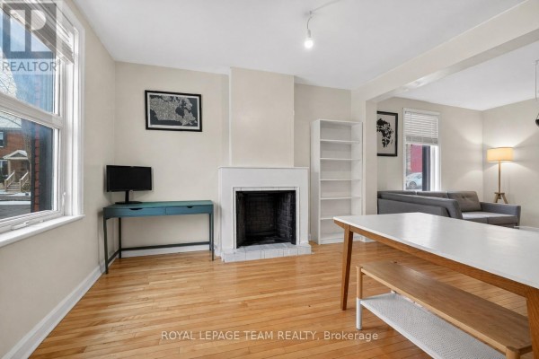 Living room with hardwood floors, fireplace, built-in bookshelf, and a sofa. - 8 Lewis Street, Ottawa