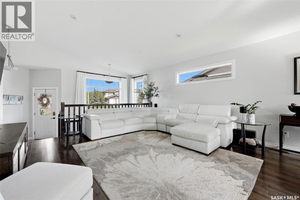 Living room with a large white sectional sofa, beige floral rug, and dark hardwood floors. - 8 Lott Road E, White City