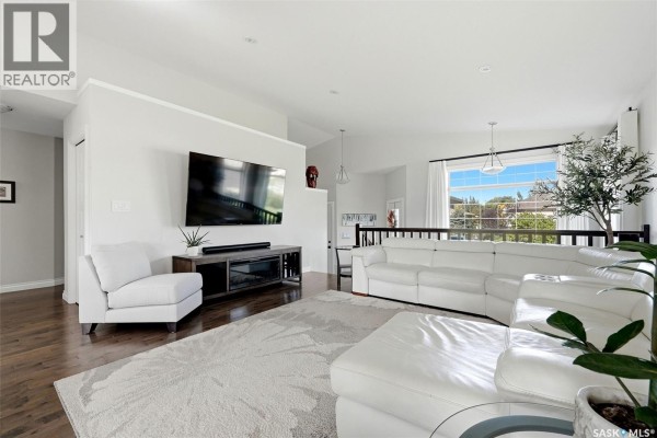 Spacious living room with a white sectional sofa, two white armchairs, and a mounted television. - 8 Lott Road E, White City