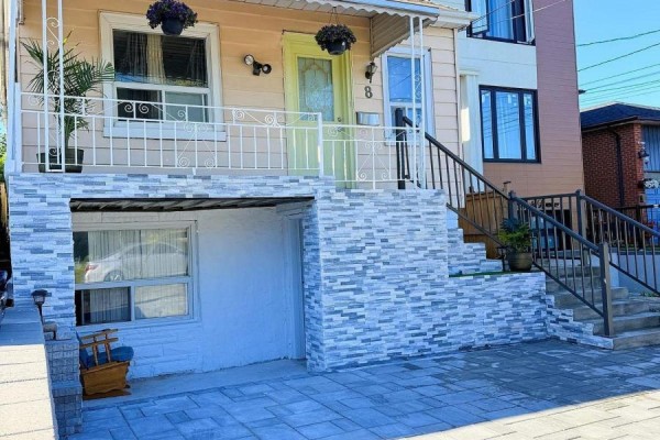 Exterior of a detached yellow house with a stone facade, driveway, and front steps. - 8 Mack Avenue, Toronto