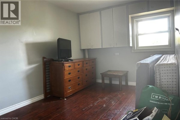 Bedroom with dark hardwood floors, a dresser, and a window with white blinds. - 8 Nelson Street, Webbwood