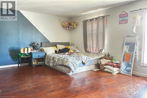 Bedroom with dark hardwood floors, a queen-size bed, and a two-tone blue and white wall. - 8 Nelson Street, Webbwood