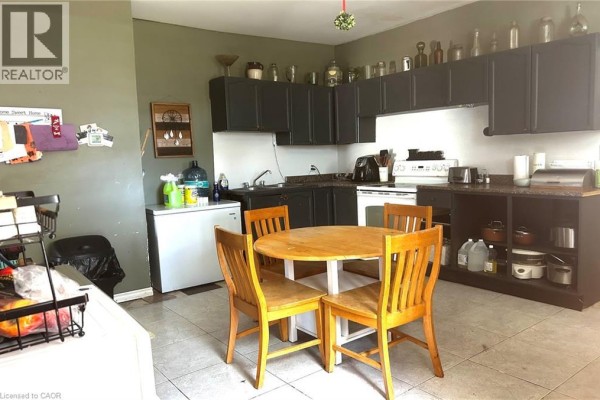 Kitchen with dark cabinets, a round wooden table and chairs, and a white refrigerator. - 8 Nelson Street, Webbwood