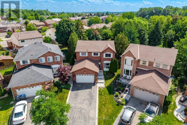 Street view of brick houses with garages on a cul-de-sac under a blue sky. - 8 Paramount Place, Brampton