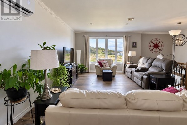 Living room with sectional sofa, recliner chairs, and a large window overlooking a landscape. - 8 Parkway Heights, Corner Brook