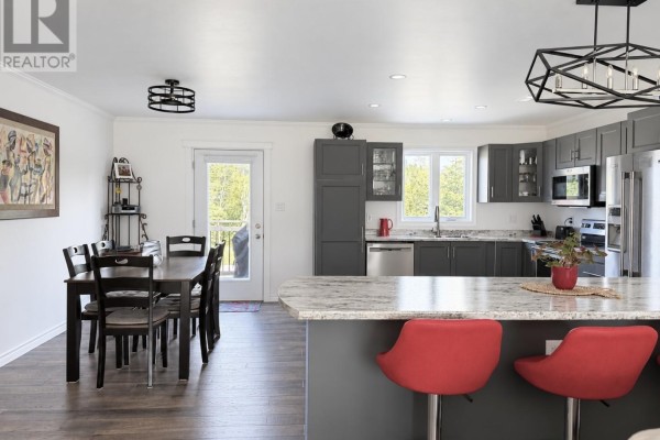 Kitchen and dining area with dark gray cabinets, island with red stools, and wooden dining table. - 8 Parkway Heights, Corner Brook