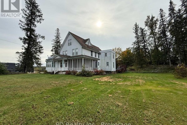 Side view of a white house with a screened-in porch and surrounding grassy lawn. - 8 Private (deloro) Road, Marmora And Lake
