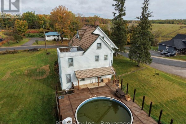 Aerial view of the rear of the house with a wooden deck, oval pool, and surrounding landscape. - 8 Private (deloro) Road, Marmora And Lake